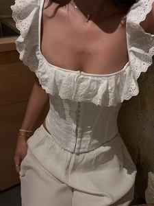 Dettaglio del corsetto bianco con ricamo inglese, spalline a balze e bottoni frontali