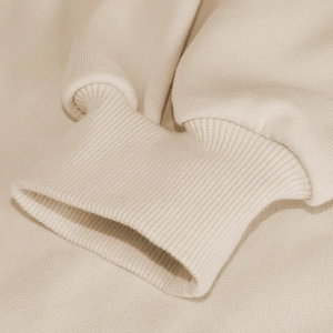 Close-up of tight ribbed cuffs on beige hooded sweatshirt showing premium knit texture