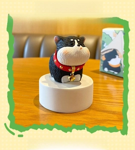 Close-up of cute husky resin figurine with a red collar and golden bell on wood base