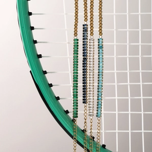 Detail of colorful rectangular zircon bracelets hanging on a green tennis racket