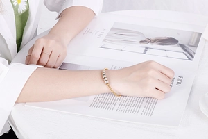 Détail du bracelet en acier titane doré avec cinq perles serties de zircones cubiques