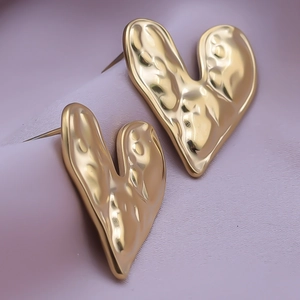 Macro shot of gold heart studs with textured hammered finish and 18K plating