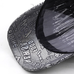 Detail of silver baseball cap with semi-transparent black visor and industrial typography