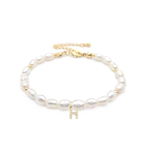Close-up of baroque pearl bracelet with gold H initial pendant and sparkling crystals