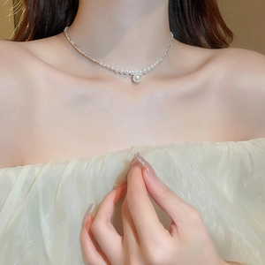 Close-up of elegant pearl necklace with zircon pendant on model neck