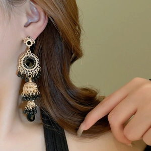Macro shot of vintage gold tassel earrings with black stones on female model ear