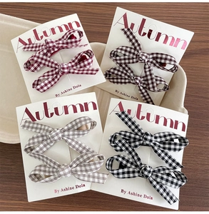 Detail view of handmade plaid bow hair clips in four autumn colors on display cards