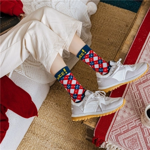 Detail of red and blue checkered knit socks featuring Nice! lettering on the cuff
