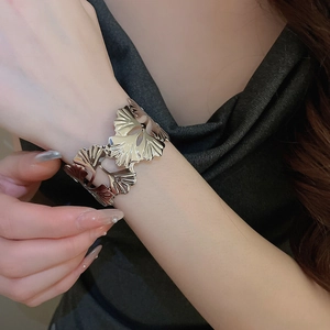 Detailed close-up of a silver ginkgo leaf open cuff bracelet on a model wrist