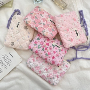 Flat lay of five floral quilted pouches in pink and beige with purple drawstrings