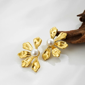 Elegant gold flower earrings with white pearl center on a minimalist grey background