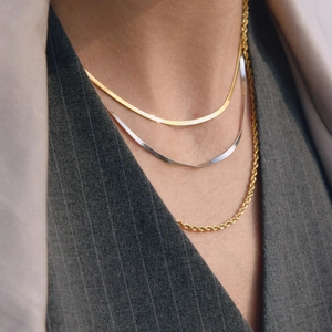 Close-up of layered gold and silver snake chains with a gold twist necklace on a model