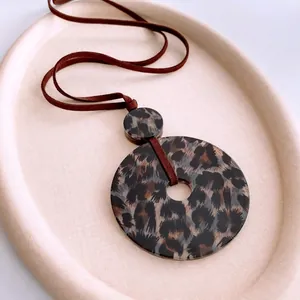 Chic leopard print acrylic circle pendant necklace with brown leather cord on tray