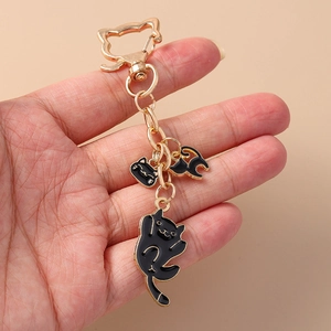 Close-up of cute black cat paw keychain with gold hardware on a beige background