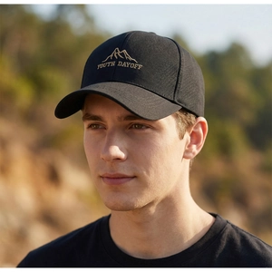 Close-up of black baseball cap with gold mountain embroidery on a side-profile model