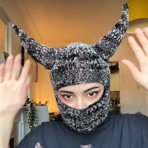 Detail of grey knitted balaclava with 3D devil horns and thick warm wool texture