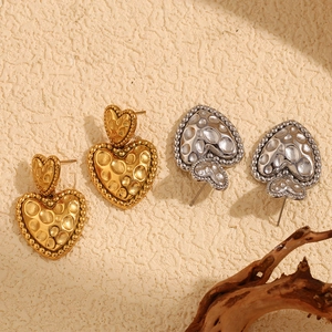 Détail des boucles d'oreilles cœur en or et argent avec une surface texturée martelée
