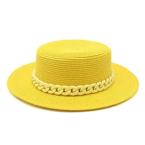 Detail of yellow flat top boater hat with decorative chain and fine straw weave texture