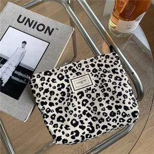 Close-up of leopard print canvas makeup bag with Pleasant Time tag on a glass table