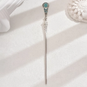 Détail d'une épingle à cheveux argentée vintage avec turquoise verte et gravures ornementées