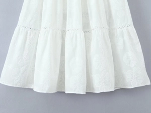 Détail de broderie florale blanche et finitions ajourées sur une mini-jupe chic