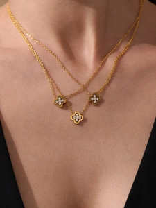 Close-up of double-layer gold necklace with sparkling clover pendants on model neck