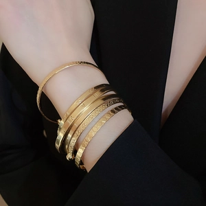 Close-up of a stacked gold bracelet set featuring LOVE engraving and textured patterns