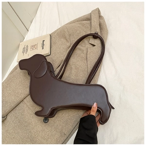 Macro detail of dark brown dachshund-shaped leather shoulder bag on a beige blazer