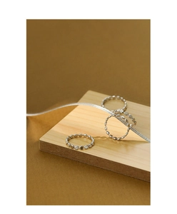 Detailed view of S925 sterling silver minimalist geometric beaded rings on a wooden stand