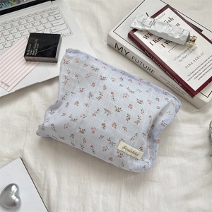 Gros plan d'une trousse en toile à fleurs sur lit avec une texture douce et coton