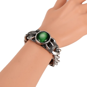 Cuban chain bracelet with green oval gemstone on model's wrist against white background