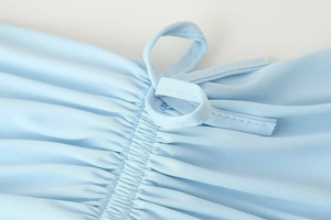 Detailed view of light blue knitted fabric with delicate ruching and drawstring elements