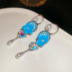 Detail view of blue resin flower earrings with colorful crystal and pearl drop pendants