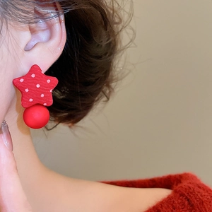 Close-up of red fabric star earrings with matte ball and polka dots on model