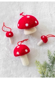Detailed view of four wool felt red mushrooms with white spots on soft plush background