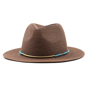 Detail of dark brown woven straw hat with turquoise beads and golden metal band accents