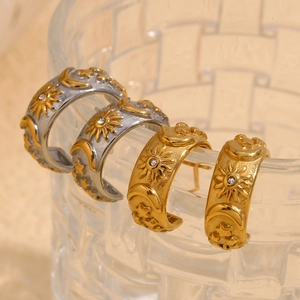 Detail of vintage C-shaped celestial earrings with sun and moon patterns hanging on glass