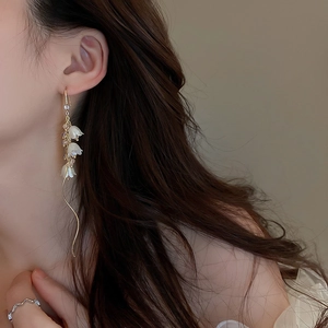 Gros plan de boucles d'oreilles muguet élégantes avec chaînes dorées sur mannequin