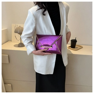 Detailed view of a purple crocodile pattern envelope clutch bag held by a model