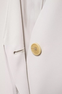 Detail of beige suit blazer showing fabric texture and round button with stitching