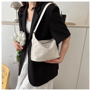 Détail d'un sac à bandoulière blanc porté par un mannequin dans un cadre moderne