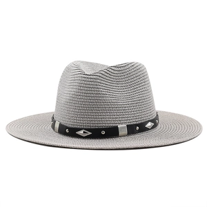 Détail du chapeau de paille gris avec ruban en cuir noir et rivets métalliques argentés