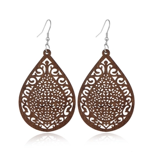 Detail of teardrop wood earrings with intricate hollow patterns on white background