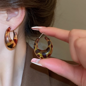Detail view of thick C-shaped leopard resin earrings with vintage amber tortoiseshell texture