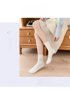 Close-up of white cotton mid-calf socks with delicate black puppy embroidery and rolled edges