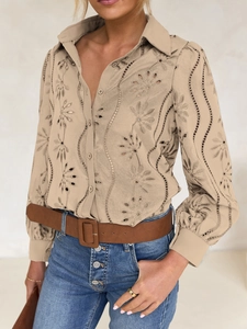 Close-up of beige embroidered button-down shirt with intricate hollow floral patterns