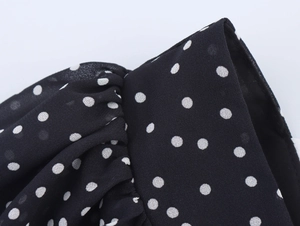 Close-up of black and white polka dot chiffon fabric with elegant pleated details