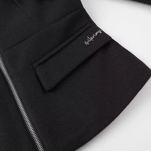 Detail of black wool jacket showing silver zipper and intricate embroidery on pocket