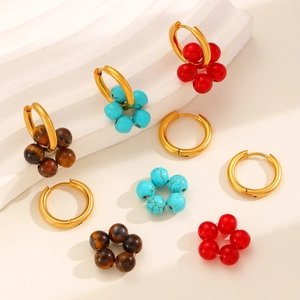 Detail of gold hoop earrings with red, turquoise and brown natural stone bead charms