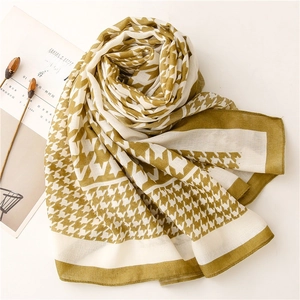 Flat lay of olive green houndstooth scarf with cotton-linen feel and aesthetic props